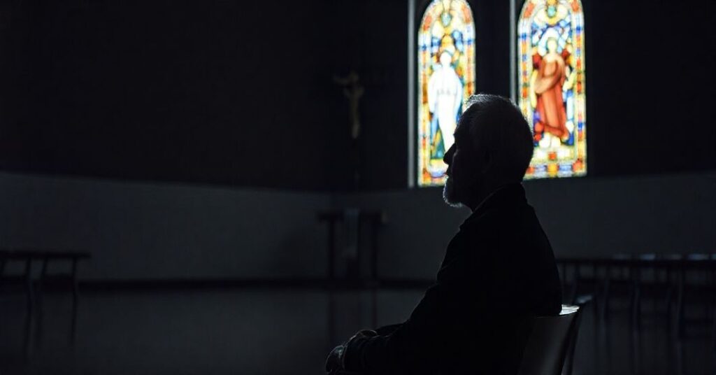 Portret Anthony'ego Hopkinsa w nowoczesnej kaplicy, odraczając się od krzyża, symbolizujący odrzucenie autorytetu Kościoła i głęboką herezję duchowości