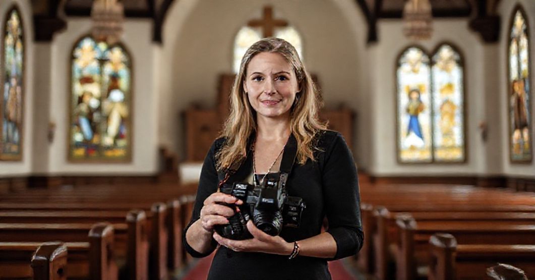 Chrześcijańska Fotograf Chelsey Nelson - Obrona Sumienia Portret chrześcijańskiej fotograf Chelsey Nelson w tradycyjnej katolickiej świątyni, trzymającej aparat z determinacją i spokojem. Symbolizuje jej zwycięstwo prawnicze przeciwko wymuszaniu uczestnictwa w homoseksualnych 'weselech'