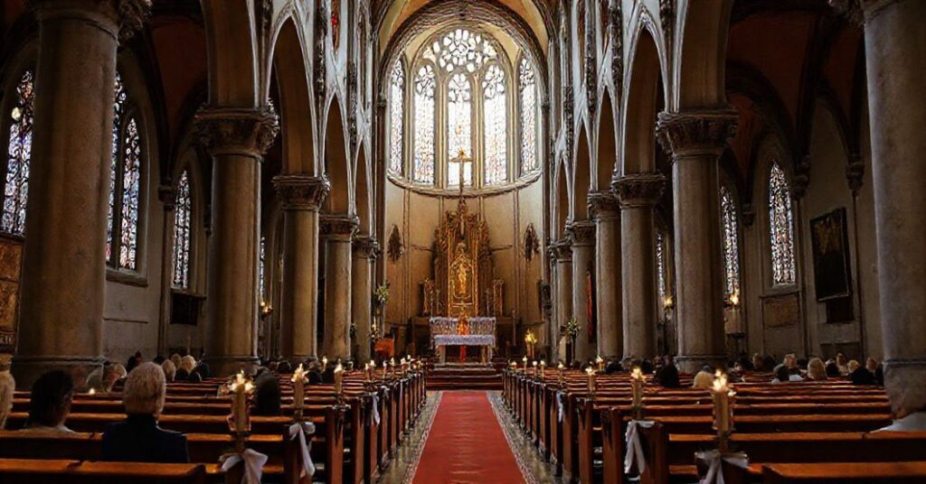 Wnętrze kościoła podczas kontrowersyjnej ceremonii bez tabernakulum, z grobowcem i „biskupem” w złotej sutannie, otoczone nieczułymi wiernymi.