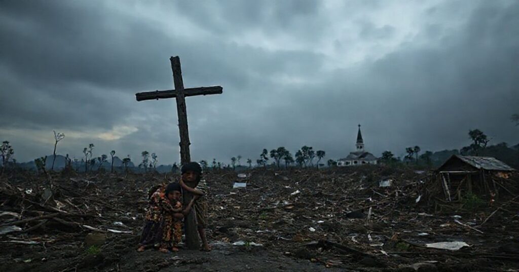 Zniszczona krajobraz Sumatra po powodzi i osuwiskach z rodziną modlącą się przy zniszczonym krzyżu