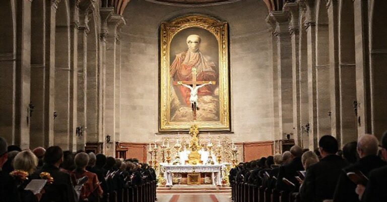 Wnętrze katedry w Kaliszu podczas rzekomej mszy za królową i władców Polski. Centralnie umieszczony krzyż w otoczeniu pustych naczyń sakralnych i portretem Mieszka III na tle. Zgromadzenie z kwiatami zamiast modlitewników.