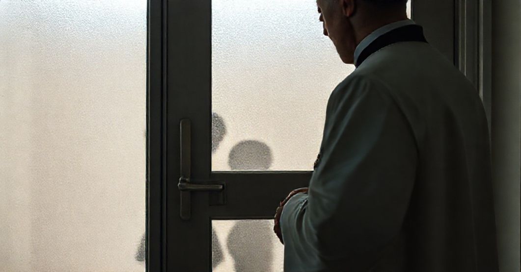 Kapelan katolicki modlący się przed zabytkowym drzwiami kliniki medycznej, trzymając krzyż z Jezusem. Scena podkreśla godność ludzkich istot i walkę Kościoła przeciwko pseudomedycznym praktykom.