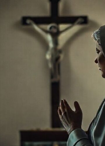 Tradycyjna katolicka kobieta modli się w kaplicy przed ukrzyżowanym Chrystusem