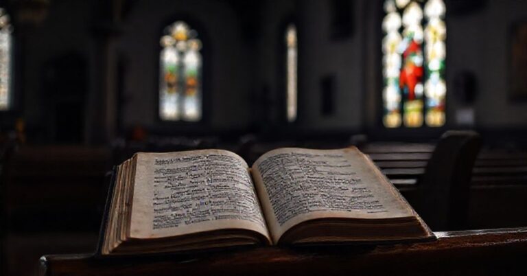 Stary kościół katolicki z otwartą księgą Modlitw z wersetem z Kazań Kapłana, w tle rozmyty artykuł o eliminacjach piłkarskich - symbolizuje marnotrawstwo światowych pasji.