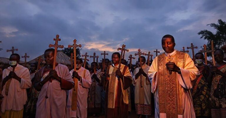 Tradycyjna procesja katolicka w afrykańskiej wiosce podczas epidemii, z księdzem w ornacie i wiernymi modlącymi się za pomocą Bożą.