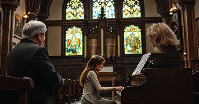 Kobieta grająca na pianinie w tradycyjnym kościele katolickim otoczona dwoma krytykami