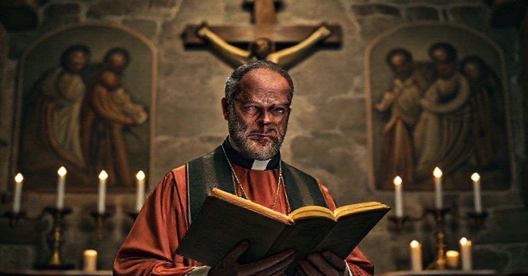 Ksiądz w tradycyjnym habicie modli się przed krzyżem w starożytnym kościele, oświetlony przez świece. Scena symbolizuje walkę z nowoczesnymi herezjami.