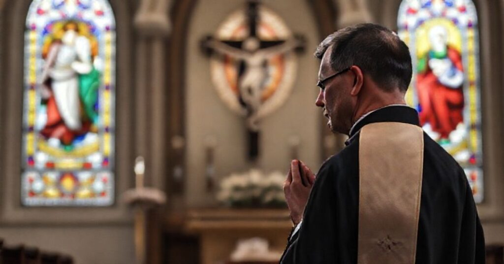 Tradycyjny ksiądz w sutannie modli się przed krzyżem w kościele z oknami witrażowymi przedstawiającymi Serce Pana Jezusa i Matkę Boską Bolesną. Scena wyraża głęboką pobożność i duchową tęsknotę.