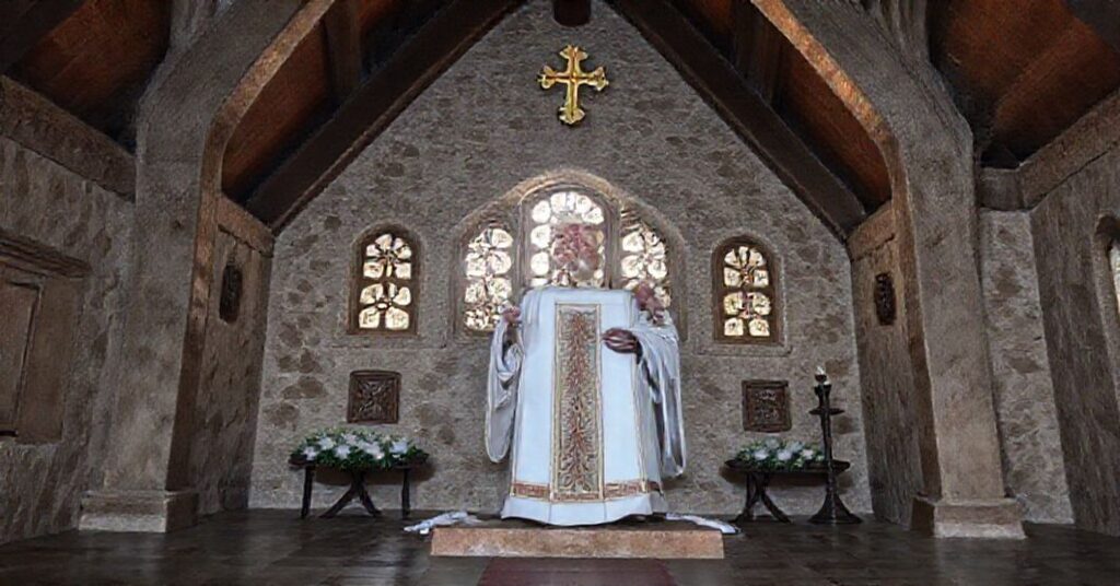 Ksiądz w ciemnym kościele trzymający krzyż przed symbolami apostazji