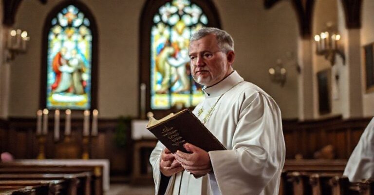 Ksiądz w biało-czarnych szatach trzyma kodeks prawa kanonicznego z 1917 roku w tradycyjnym kościele katolickim.