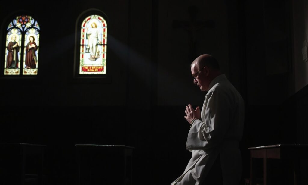 Ciemna fotografia sali egzekucyjnej w Teksasie z księdzem w sutannie modlącym się przed egzekucją Jamesa Garfielda Broadnaxa.