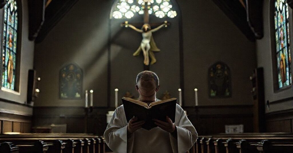 Ksiądz w sutannie czyta brewiarz w tradycyjnym kościele z pustym tabernakulum i krzyżem z Chrystusem cierpiącym.