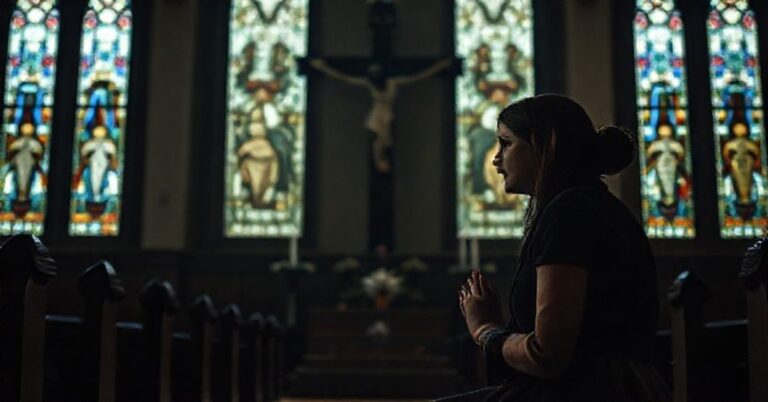 Kobieta modląca się przed krzyżem w tradycyjnym koście katolickim, symbolizująca niesprawiedliwłość i represje.