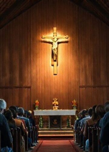 Modlitwa katolicka o ochronę przed cyberprzestępcami Wnętrze tradycyjnego kościoła katolickiego z krzyżem w centralnym miejscu, otoczone grupą modlącej się społeczności wiernych.