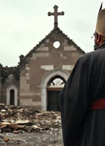 Ksiądz w tradycyjnych paramentach modli się przed zniszczonym kościołem w krajach dotkniętych wojną. Symbolizuje cierpienie prześladowanych katolików.