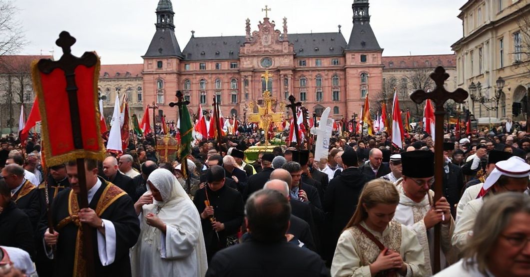 Procesja katolicka w Warszawie z grupą ludzi trzymających transparenty i krzyże przed Zamkiem Królewskim.