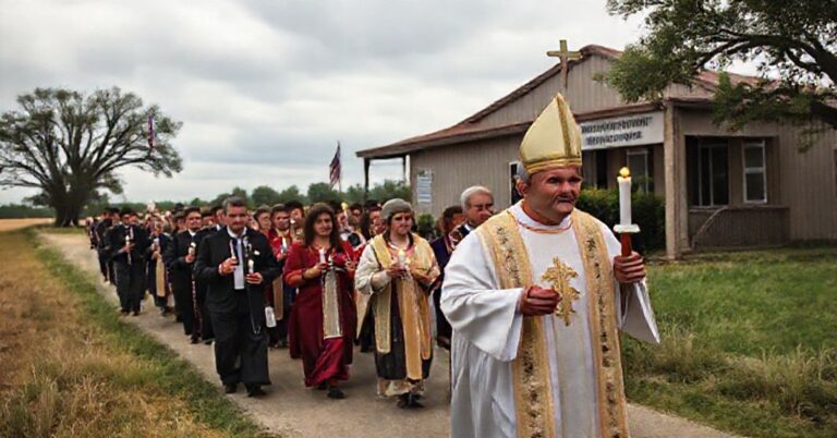 Pielgrzymka katolicka w Teksasie z modlącymi się wiernymi i księdzem w ornaty przesuwającymi się obok budynku hrabstwa z tablicą 'Hrabstwo Howard - Azyl dla Nienarodzonych Ordynacja'