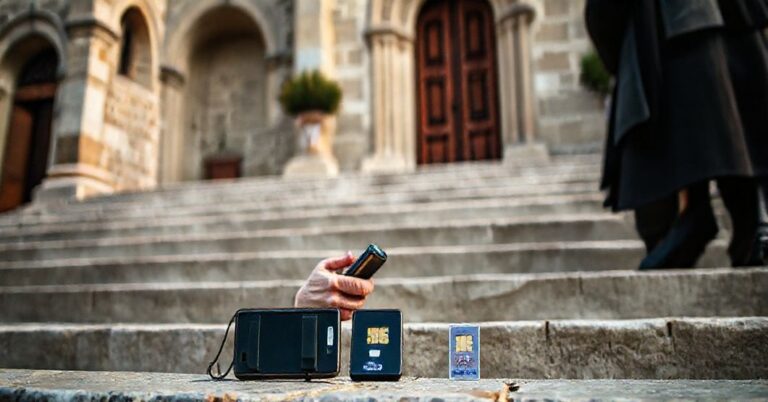 Katolicki pielgrzym modli się przed europejskim kościołem z różańcem w ręku, z nieużywanym telefonem i kartą eSIM na schodach.