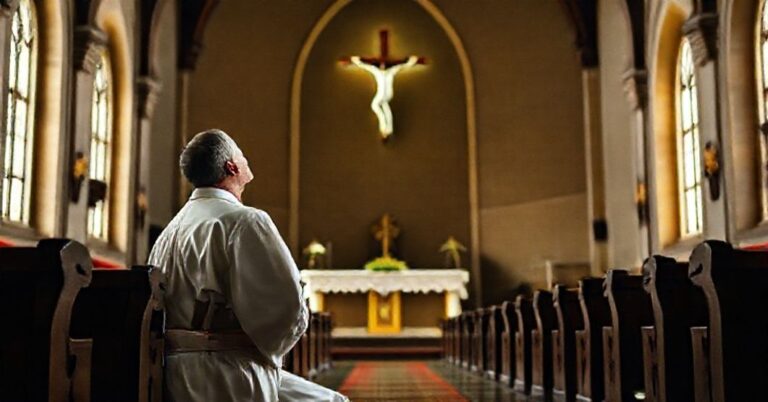 Mężczyzna w tradycyjnym stroju katolickim modli się przed krzyżem w kościele w tradycyjnym stylu