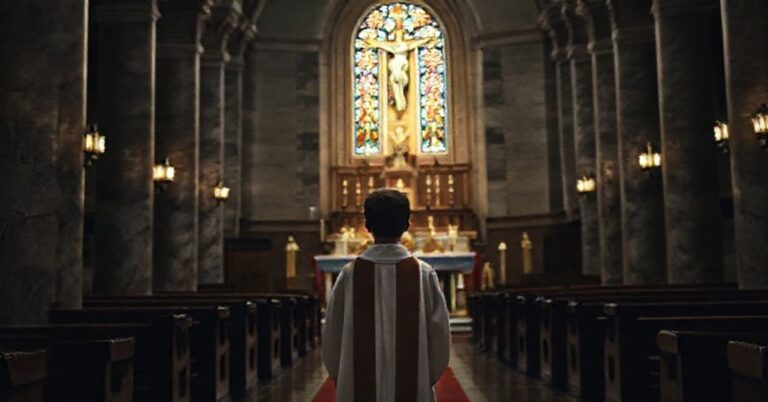 Młody ministrant w liturgicznych szatach modlący się przed ołtarzem w tradycyjnym kościele