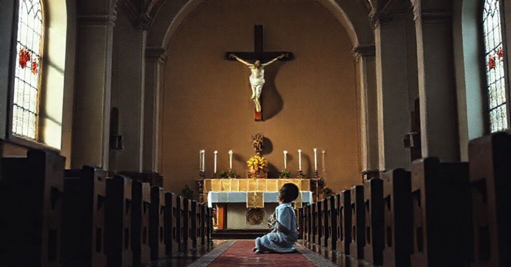 Młody chłopiec modli się w tradycyjnym kościele katolickim przed krzyżem, symbolizującym prawdziwe męczeństwo i odrzucenie fałszywych nauk neo-moderneistów.