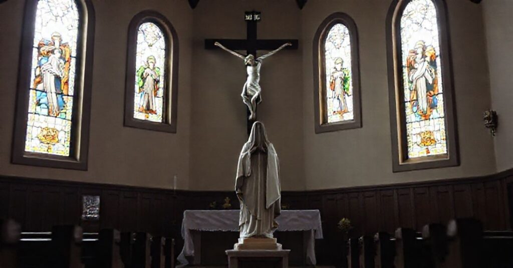 Tradcyjny wnętrze kaplicy katolickiej z rzeźbą Matki Bożej u stóp krzyża Chrystusa