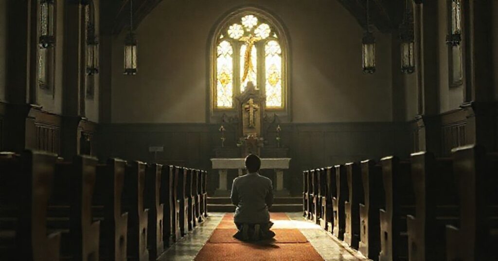 Wnętrze tradycyjnego kościoła z samotną postacią modlącej się przed tabernakulum. Scena symbolizuje duchową pustkę współczesnego świata w kontekście artykułu Olgi Drendy.
