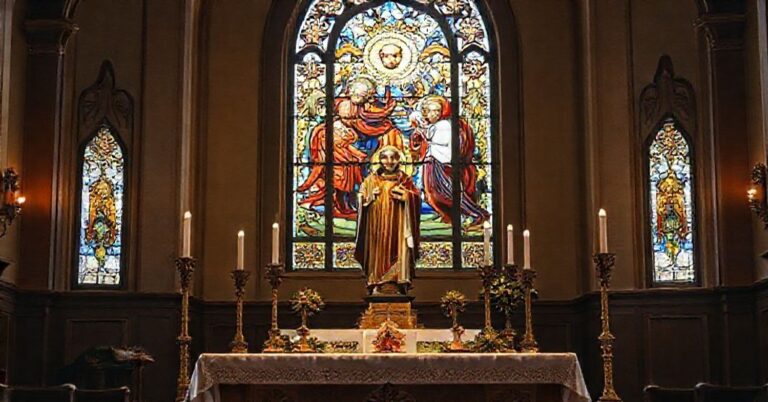 Ołtarz katolicki z tradycyjnymi elementami liturgicznymi i posągiem św. Piotra Chryzologa na tle witrażu przedstawiającego Incarnację Chrystusa.