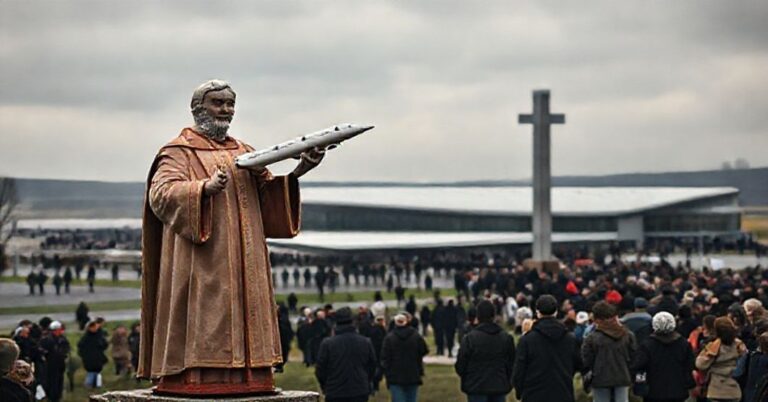 Zdjęcie przedstawiające sanktuarium w Knock w Irlandii z widoczną statuą ks. Jamesa Horana trzymającego model samolotu na tle terminalu lotniska. Scena symbolizuje kompromis teologiczny między pobożnością a komercją.