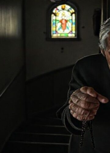 Starsi w opuszczeniu - gdzie jest katolicka miłość? Starsi katolicka para wspinająca się po ciemnych schodach z różańcem w rękach, symbolizując opuszczenie i potrzebę katolickiej miłości.