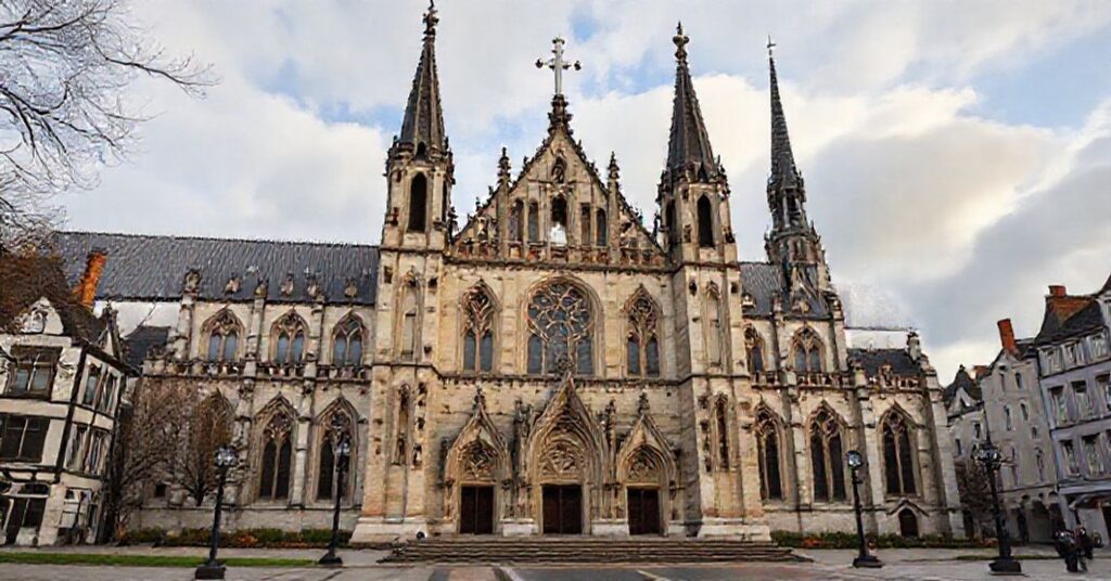 Stary katolicki kościół w Anglii z widokiem na ruiny anglikańskich sakralnych budowli, symbolizujący walkę o prawdziwą wiarę.