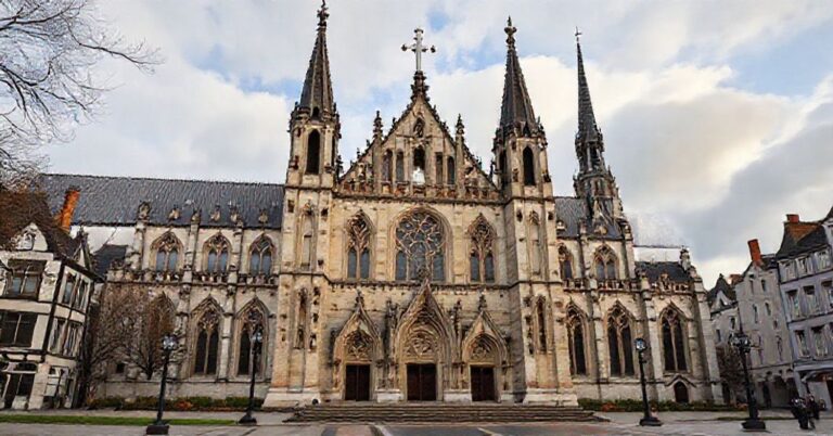 Stary katolicki kościół w Anglii z widokiem na ruiny anglikańskich sakralnych budowli, symbolizujący walkę o prawdziwą wiarę.