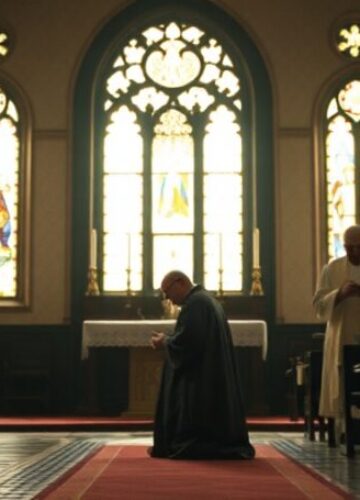 Synod Wrocławski: Reorganizacja bez Chrystusa Wnętrze tradycyjnego kościoła z kapłanem modlącego się przed tabernakulum i grupą nowoczesnych duchownych dyskutujących dokumenty w tle.