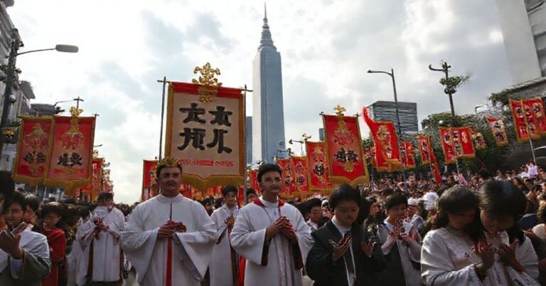 Procesja katolicka w Tajpej z udziałem duchownych i wiernych modlących się przed wieżowcem Taipei 101.