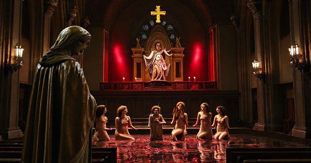 Wnętrze katolickiego kościoła z rzeźbą Matki Boskiej Bolesnej w pierwszym planie, patrzącą z żalem na scenę teatralną z aktorkami w nieprzyzwoitych kostiumach i sztucznym kałem.