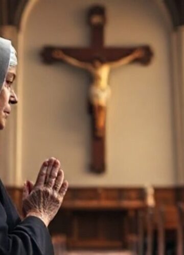 Tradycyjna katolicka scena modlitewna w kościele Relewantna scena w tradycyjnym katolickim kościele z zakonnicą modlącą się przed krucyfiksem, symbolizująca głębokie skupienie i pobożność w duchu katolickim