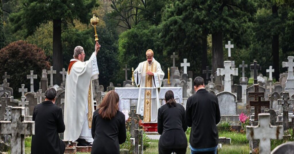 Scena cmentarza katolickiego z tradycyjną Mszą św. za zmarłych, podkreślającą modlitwę za dusze w czyśćcu i nadprzyrodzone rzeczywistości śmierci i życia wiecznego.