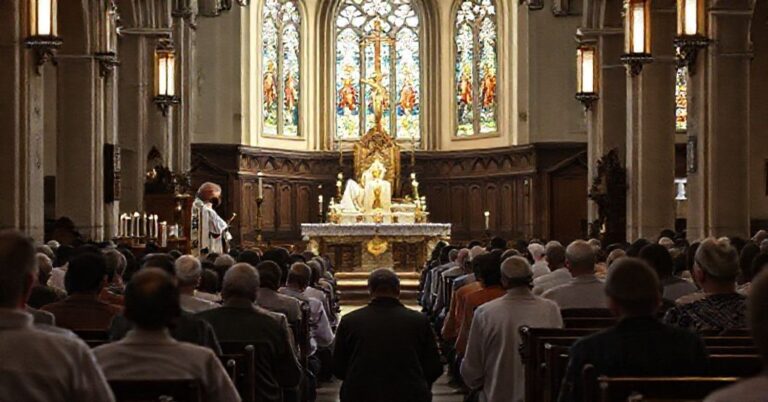 Wnętrze tradycyjnego kościoła katolickiego z celebracją Mszy Trydenckiej przez kapłana w ornatach. Wierni modlący się klęcząc w atmosferze głębokiej pobożności.