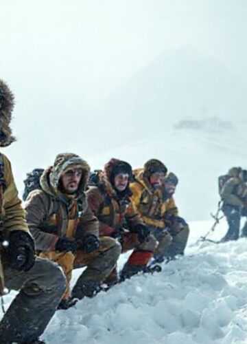 Turysci uwięzieni na Mount Everest w świetle katolickiej refleksji Grupa narciarzy uwięzionych w śnieżnej burzy na stoku Mount Everestu z niepokojem patrzą w dół. Na tle widoczny odległy klasztor buddyjski.