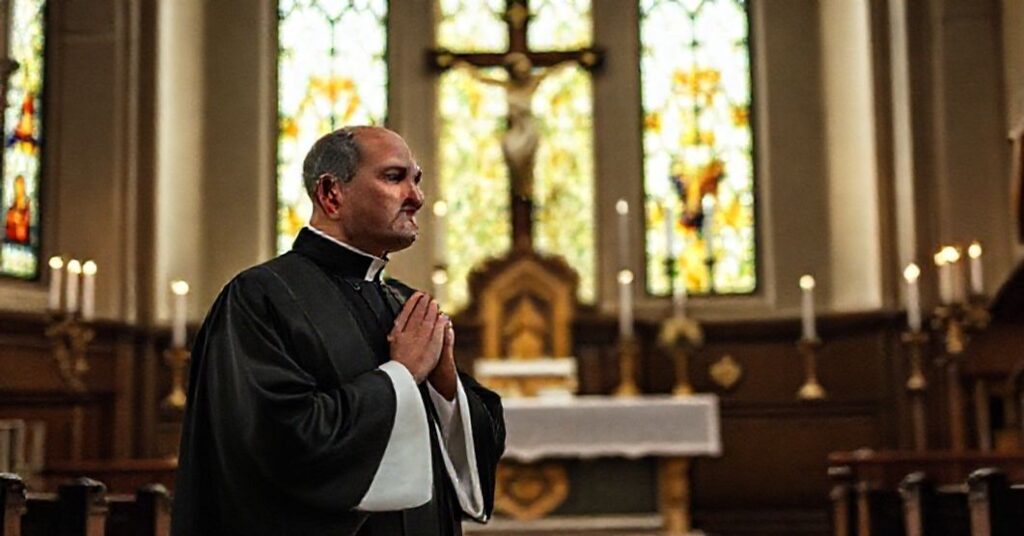 Czarny habit kleryk w tradycyjnym stroju kapłańskim stoi przed krzyżem z pokorną postawą modlitwy. W tle ołtarz z zapalonymi świecami i tabernakulum symbolizujący obecność Najświętszego Sakramentu. Scena osadzona w tradycyjnym kościele z witrażami przepuszczającymi miękkie, pobożne światło.