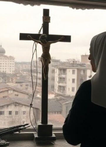 Katolicka zakonnica modląca się w kaplicy z widokiem na Ukrainę - obraz poważny i pełen szacunku Zdjęcie realistycznej, pełnej szacunku katolickiej zakonnicy modlącej się przed krucyfiksem w kaplicy, z ukraińskim miastem w tle, podkreślające potrzebę Królowania Chrystusa w obliczu kryzysu