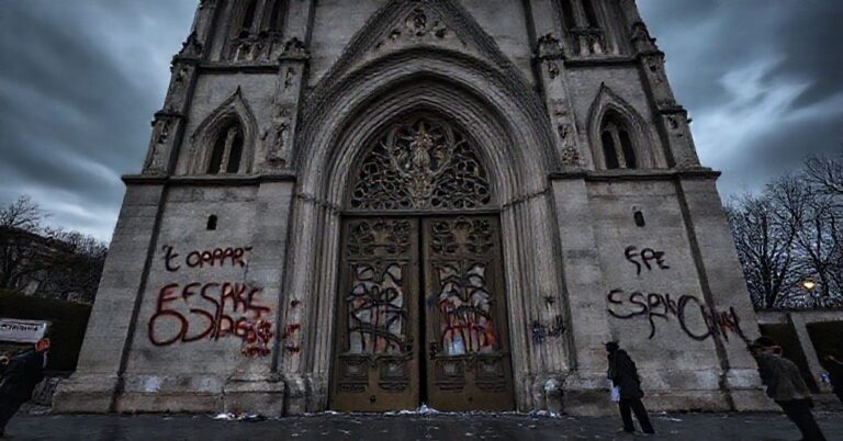 Zbezczeszczona bazylika Sacré-Cœur w Lourdes z nawalonymi drzwiami i blaszfemicznymi napisami